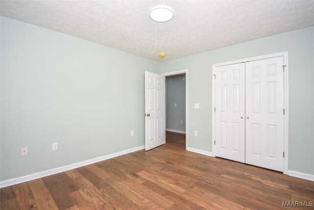 6790 Upper River Rd, Tallassee, AL 36078 - unfurnished bedroom with wood finished floors, baseboards, a textured ceiling, and a closet