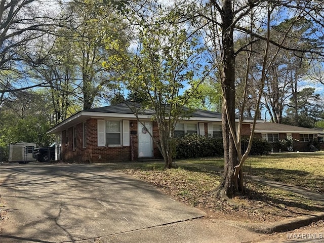 view of front of house with brick siding, driveway, and a front lawn