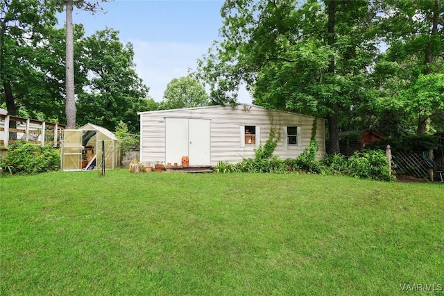 view of greenhouse with a lawn and a shed