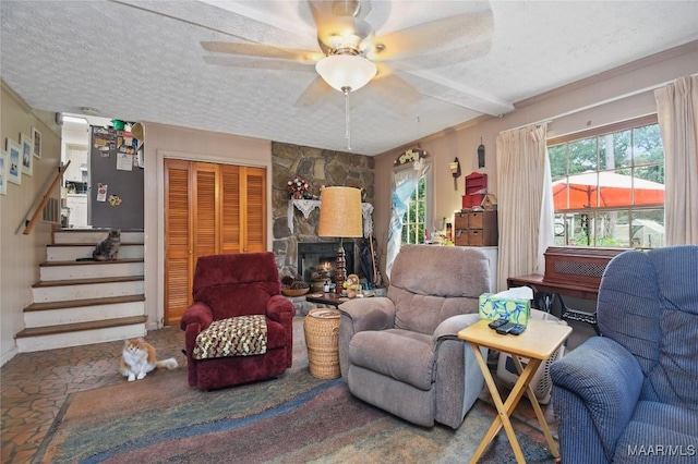 living area with a textured ceiling, stairway, ceiling fan, and a fireplace