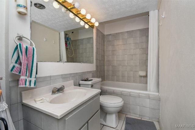 full bath featuring tiled shower / bath, tile patterned flooring, a textured ceiling, toilet, and vanity