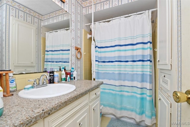 full bath with wallpapered walls, vanity, and curtained shower