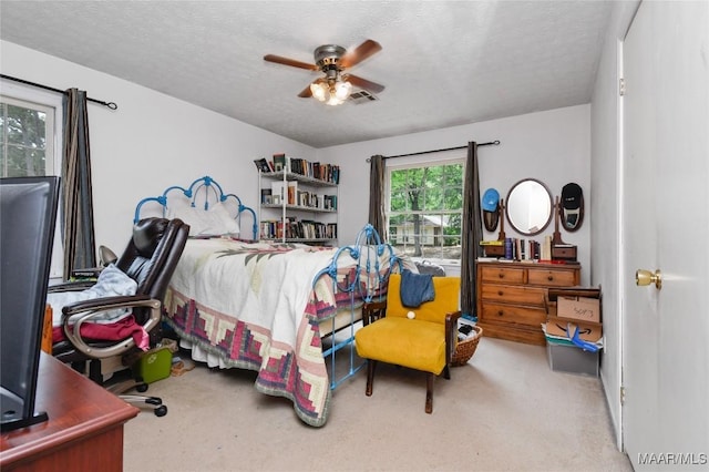 carpeted bedroom featuring a textured ceiling and a ceiling fan