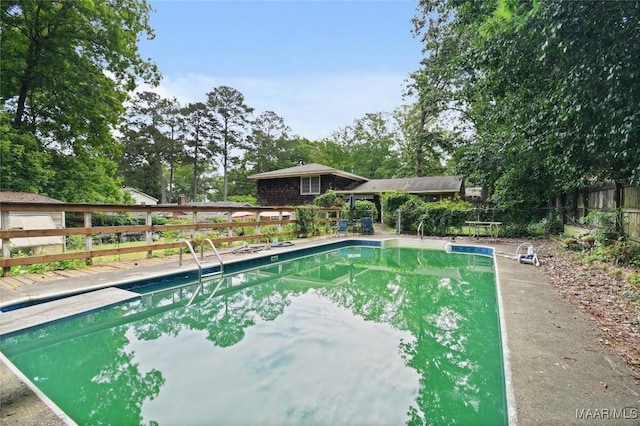 view of swimming pool featuring fence and a diving board