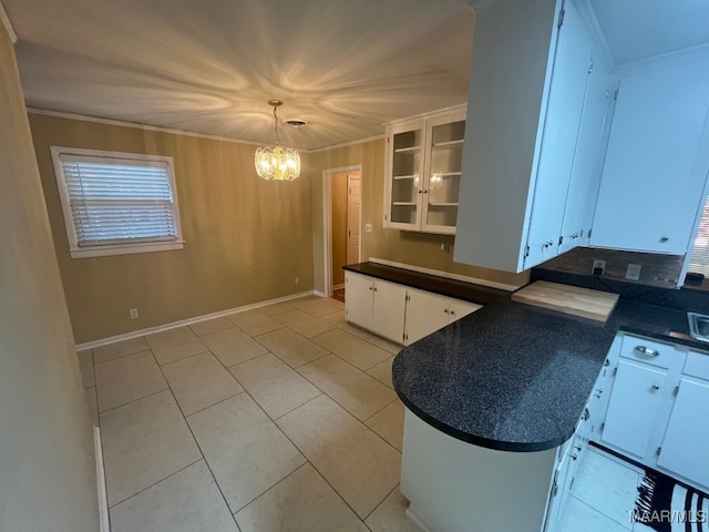kitchen with a chandelier, dark countertops, white cabinetry, crown molding, and a peninsula