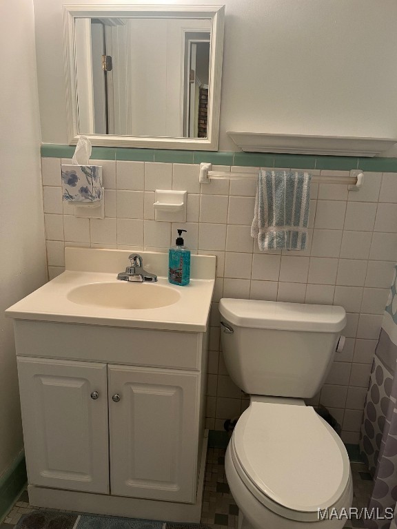 bathroom with toilet, vanity, and tile walls