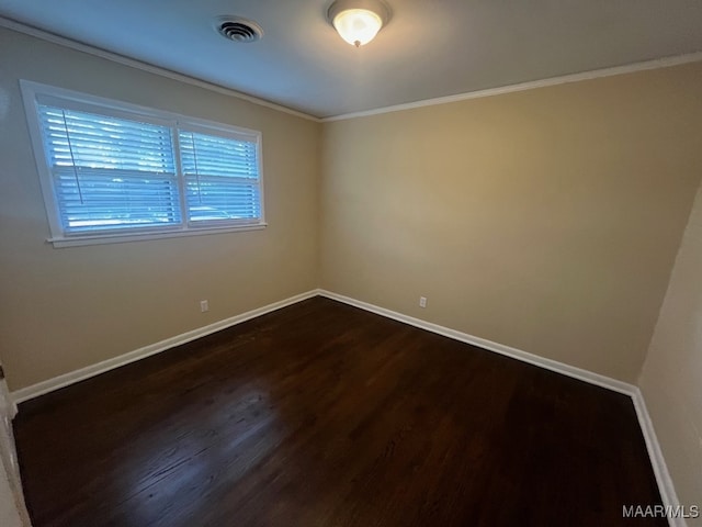 empty room with dark wood-style flooring, baseboards, and ornamental molding
