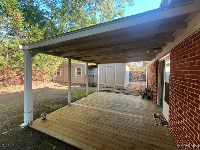 wooden terrace with an outbuilding, a storage unit, and fence