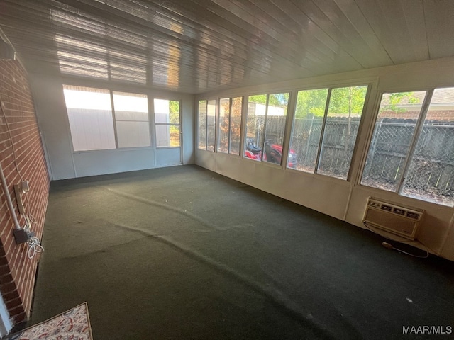 unfurnished sunroom featuring an AC wall unit, healthy amount of natural light, and carpet flooring