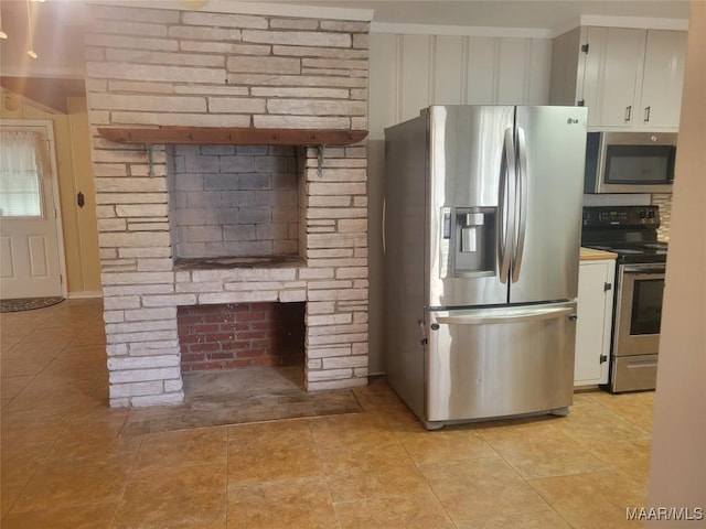 kitchen featuring appliances with stainless steel finishes, a fireplace, and white cabinetry