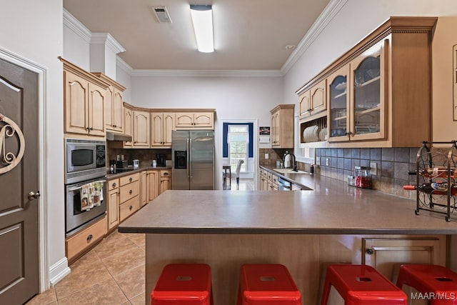 65 Copper Ridge Ct, Deatsville, AL 36022 - kitchen with stainless steel appliances, a peninsula, a kitchen bar, glass insert cabinets, and tasteful backsplash