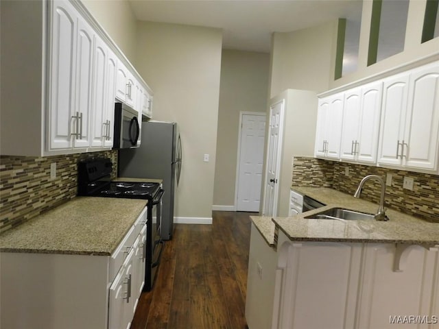 kitchen featuring black range with electric stovetop, a sink, light stone countertops, and a peninsula