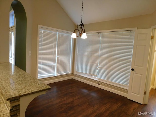 unfurnished dining area with a chandelier, arched walkways, dark wood-style flooring, vaulted ceiling, and baseboards