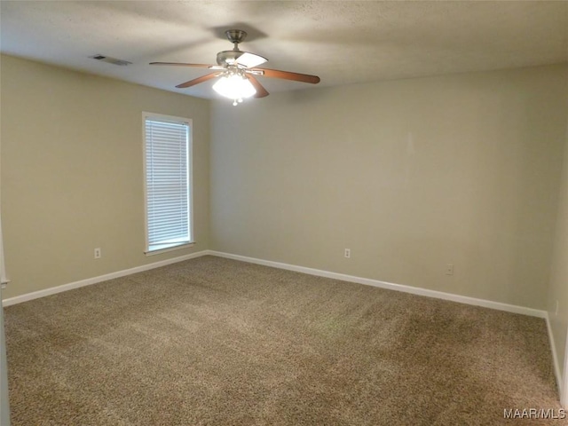 empty room with carpet, a ceiling fan, and baseboards
