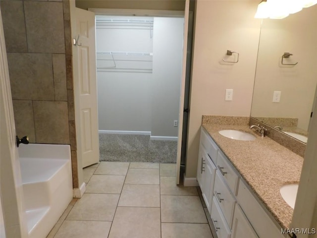bathroom with double vanity, baseboards, tile patterned floors, and a walk in closet