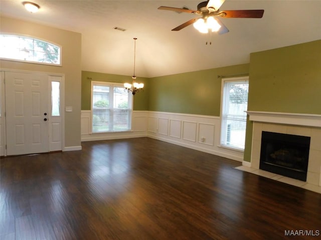 entryway with a chandelier, a wainscoted wall, a tiled fireplace, ceiling fan, and dark wood-style flooring