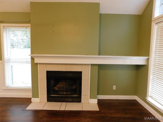 detailed view of wood finished floors, baseboards, and a fireplace
