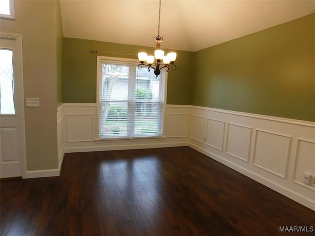 unfurnished dining area featuring vaulted ceiling, a chandelier, wainscoting, healthy amount of natural light, and dark wood-style floors