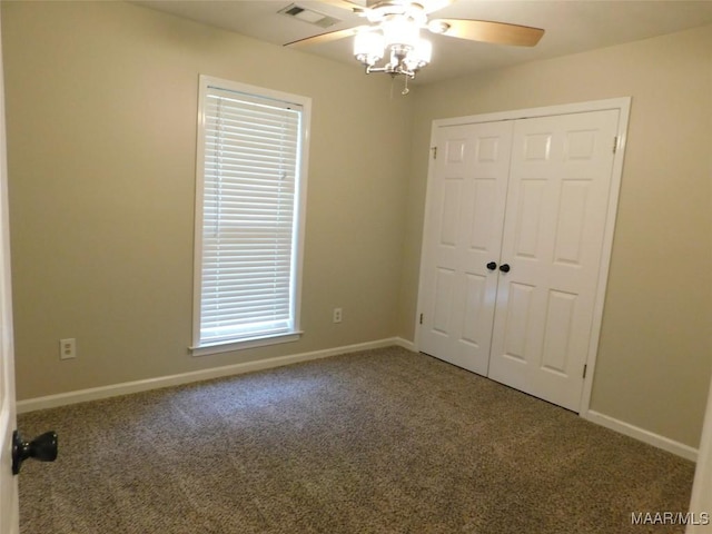 unfurnished bedroom with carpet floors, a closet, baseboards, and a ceiling fan