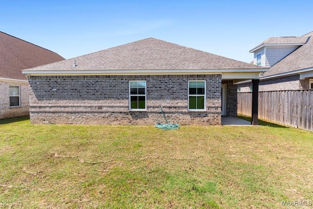 rear view of property featuring brick siding, a shingled roof, and a patio area