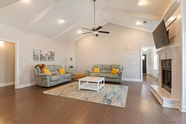 living area with dark wood-style floors, a ceiling fan, a fireplace with raised hearth, beamed ceiling, and baseboards