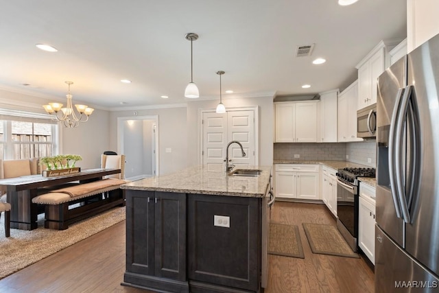 kitchen with stainless steel appliances, a sink, ornamental molding, dark wood finished floors, and white cabinetry