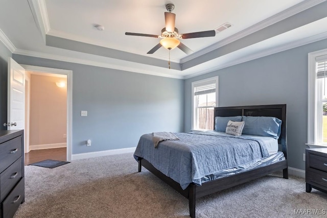bedroom with ornamental molding, a raised ceiling, carpet floors, baseboards, and a ceiling fan