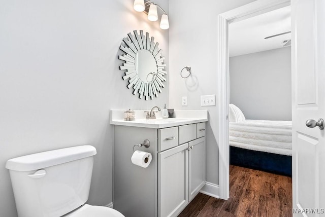 ensuite bathroom featuring toilet, vanity, and wood finished floors