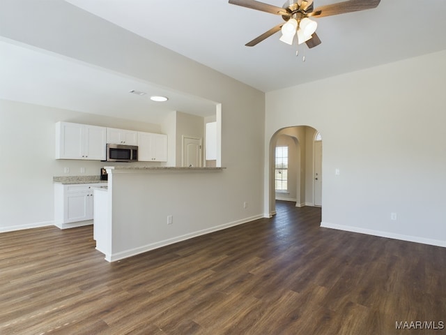 2045 Dawsons Mill Ln, Prattville, AL 36067 - unfurnished living room featuring a ceiling fan, arched walkways, dark wood-type flooring, and baseboards