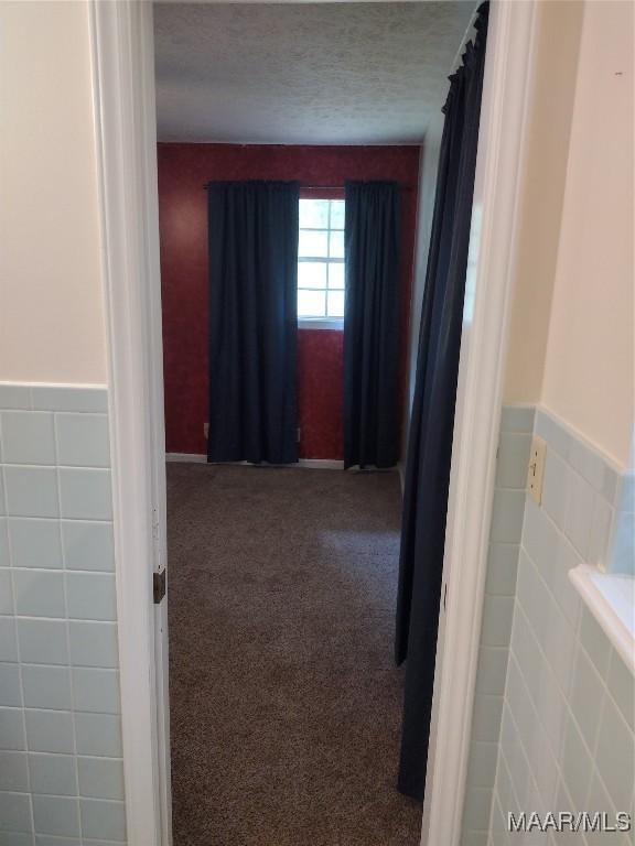 3950 Main St, Millbrook, AL 36054 - hallway with tile walls, a textured ceiling, wainscoting, and carpet