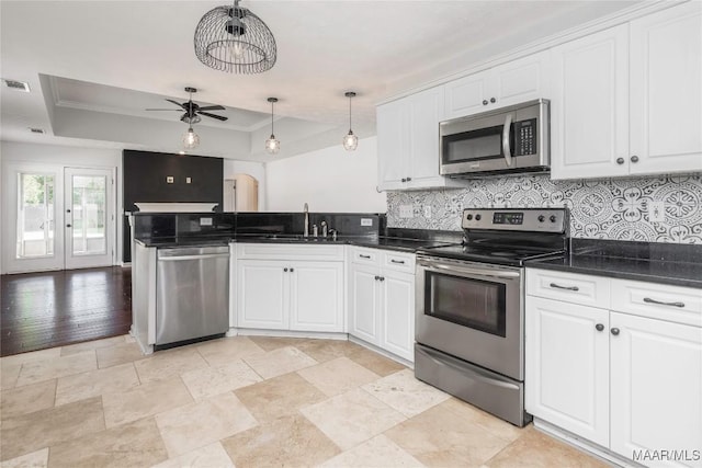 1600 Hawthorne Ln, Prattville, AL 36066 - kitchen with appliances with stainless steel finishes, a tray ceiling, a peninsula, tasteful backsplash, and white cabinets