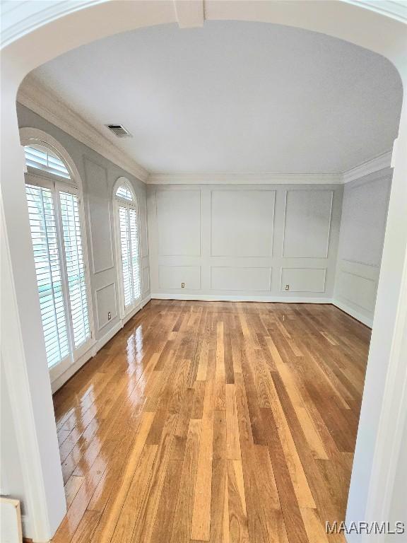 49 Berkeley Rd, Selma, AL 36701 - empty room featuring a decorative wall, arched walkways, light wood-style floors, and ornamental molding