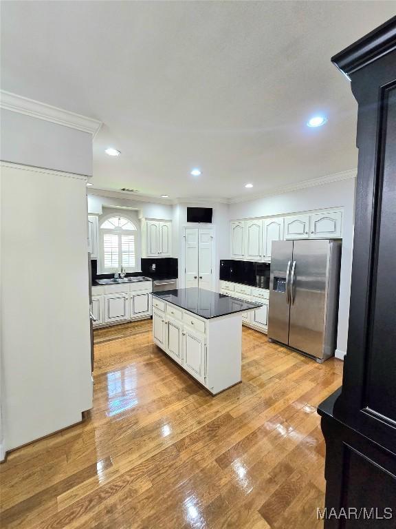 49 Berkeley Rd, Selma, AL 36701 - kitchen with stainless steel refrigerator with ice dispenser, ornamental molding, dark countertops, white cabinetry, and a kitchen island