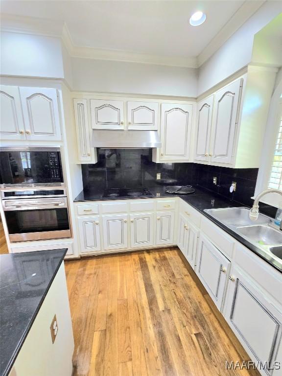 49 Berkeley Rd, Selma, AL 36701 - kitchen featuring oven, built in microwave, ornamental molding, black electric cooktop, and white cabinetry