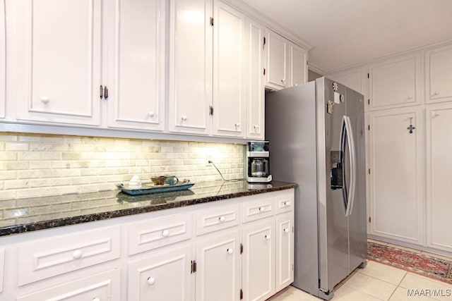 kitchen with stainless steel fridge with ice dispenser, white cabinets, dark stone counters, and light tile patterned floors