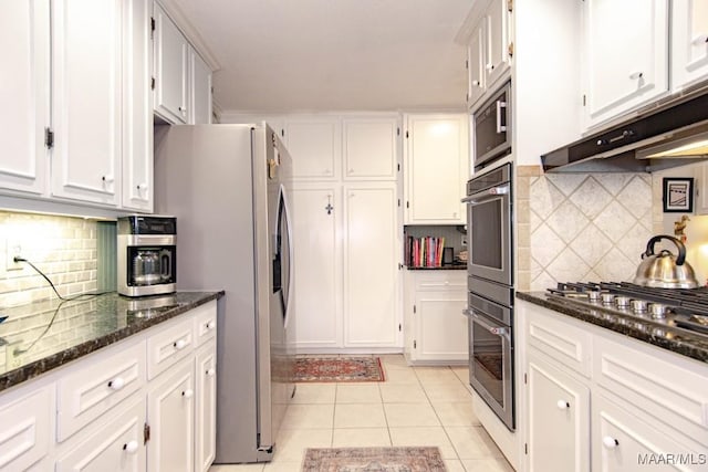 kitchen with white cabinetry, backsplash, light tile patterned floors, and dark stone countertops