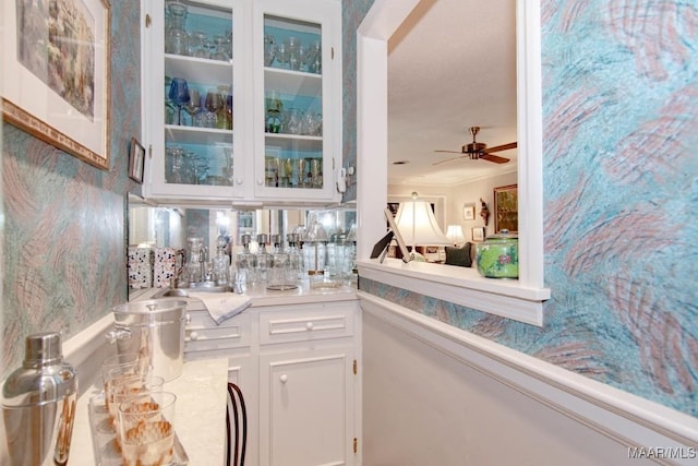 bar area featuring a sink, a ceiling fan, and crown molding