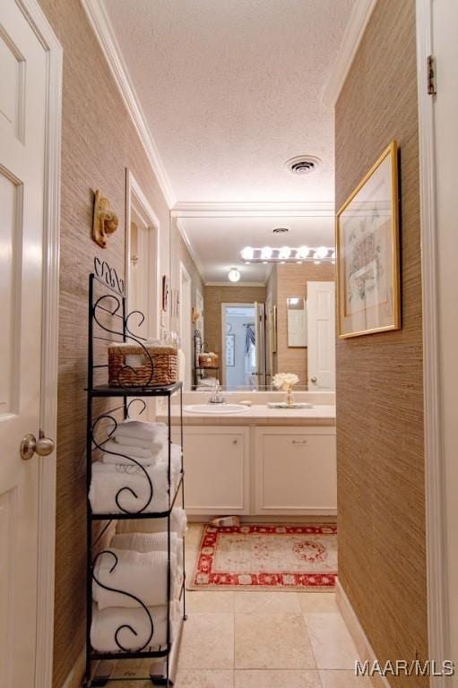 bathroom featuring ornamental molding, double vanity, tile patterned floors, and a textured ceiling