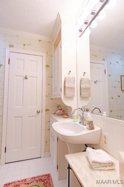 bathroom featuring crown molding, a textured ceiling, tile patterned floors, and a sink