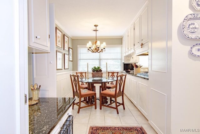 dining space with a chandelier, light tile patterned floors, ornamental molding, and a decorative wall