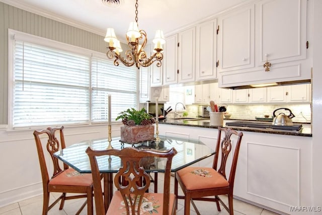dining area with a chandelier, light tile patterned floors, and ornamental molding