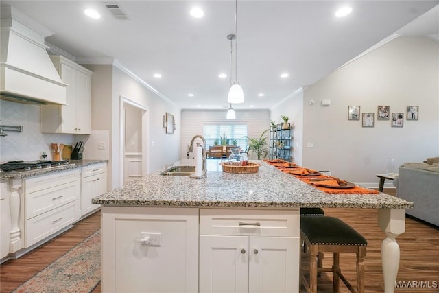 1412 Wildlife Way, Prattville, AL 36066 - kitchen with stainless steel gas cooktop, custom range hood, wood finished floors, a sink, and decorative backsplash