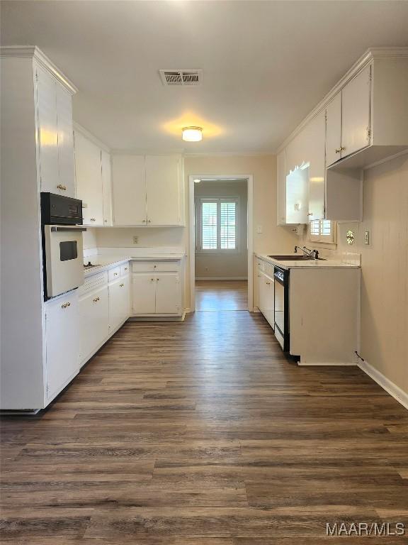 305 Sterling Dr, Montgomery, AL 36109 - kitchen featuring white oven, dark wood finished floors, a sink, black dishwasher, and white cabinetry