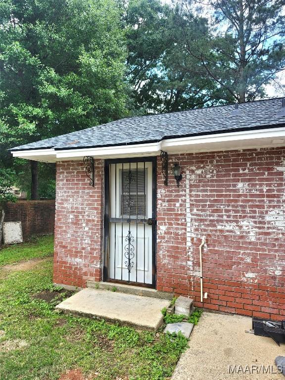 305 Sterling Dr, Montgomery, AL 36109 - view of exterior entry featuring brick siding, roof with shingles, and fence