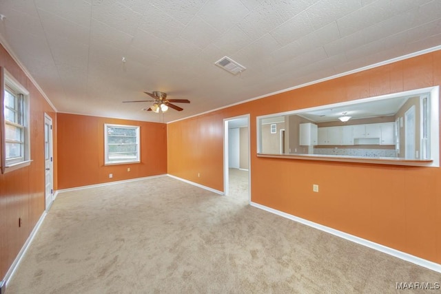 unfurnished living room featuring ornamental molding, carpet floors, a ceiling fan, and baseboards