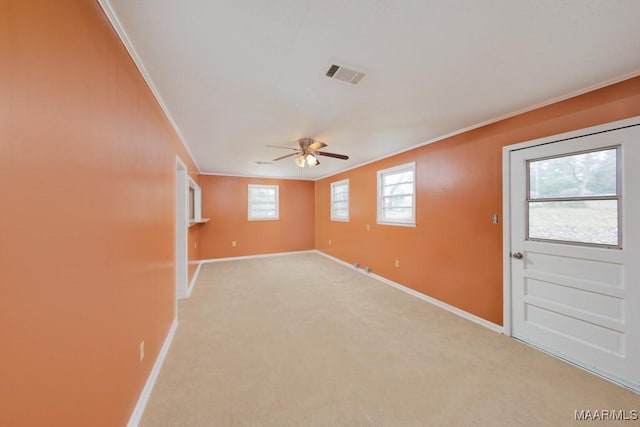 empty room featuring crown molding, a ceiling fan, baseboards, and light colored carpet