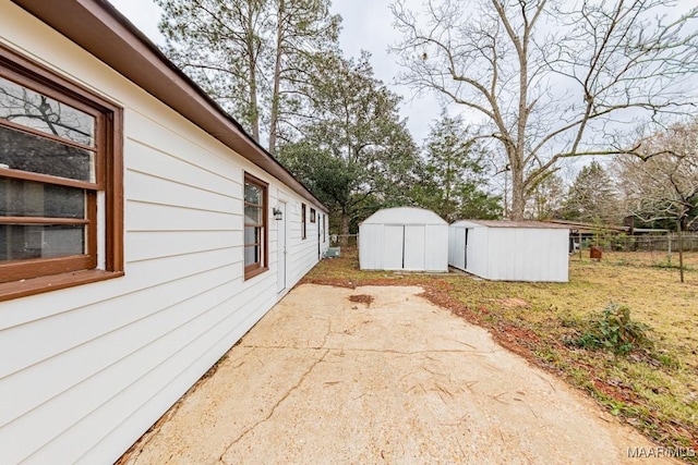 view of side of property featuring a storage shed, a patio, an outdoor structure, and fence