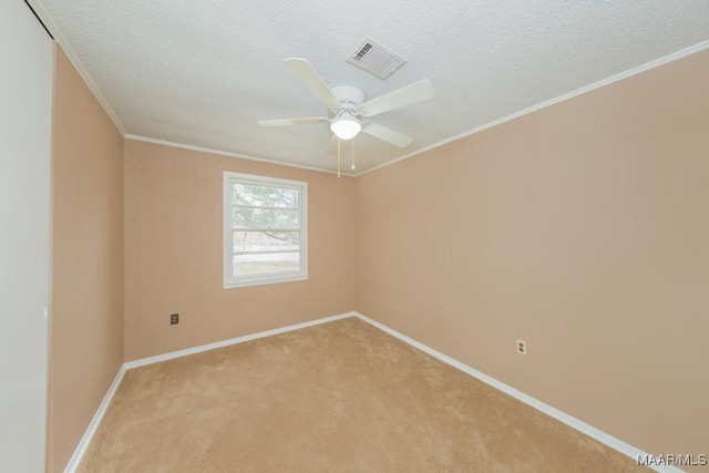 empty room featuring light carpet, baseboards, a ceiling fan, a textured ceiling, and crown molding