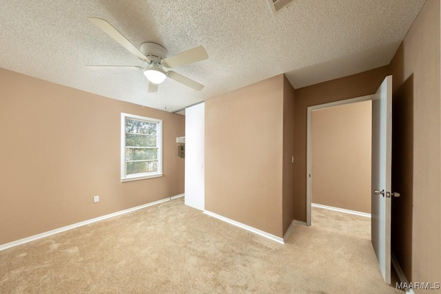 unfurnished room featuring light colored carpet, ceiling fan, a textured ceiling, and baseboards