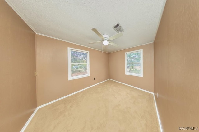 carpeted empty room featuring healthy amount of natural light, baseboards, ceiling fan, ornamental molding, and a textured ceiling